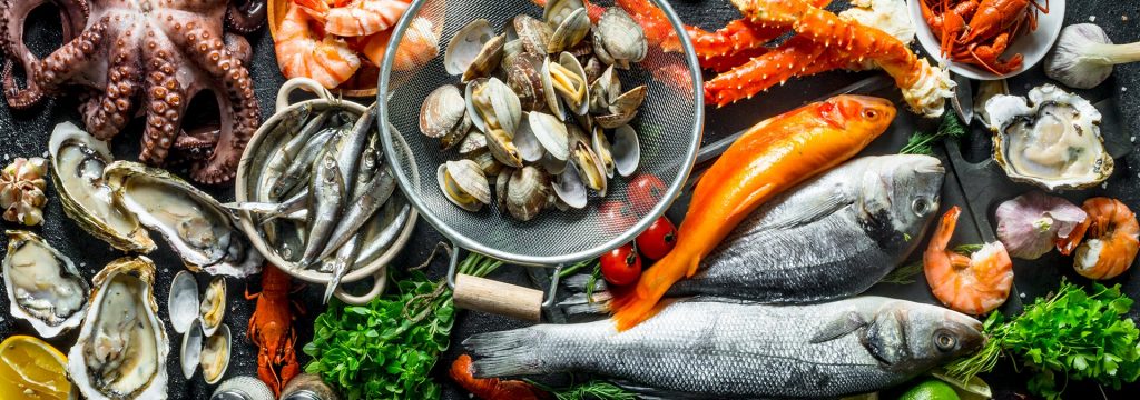 Морепродукты - креветки, рыба, морская капуста на красивой тарелке